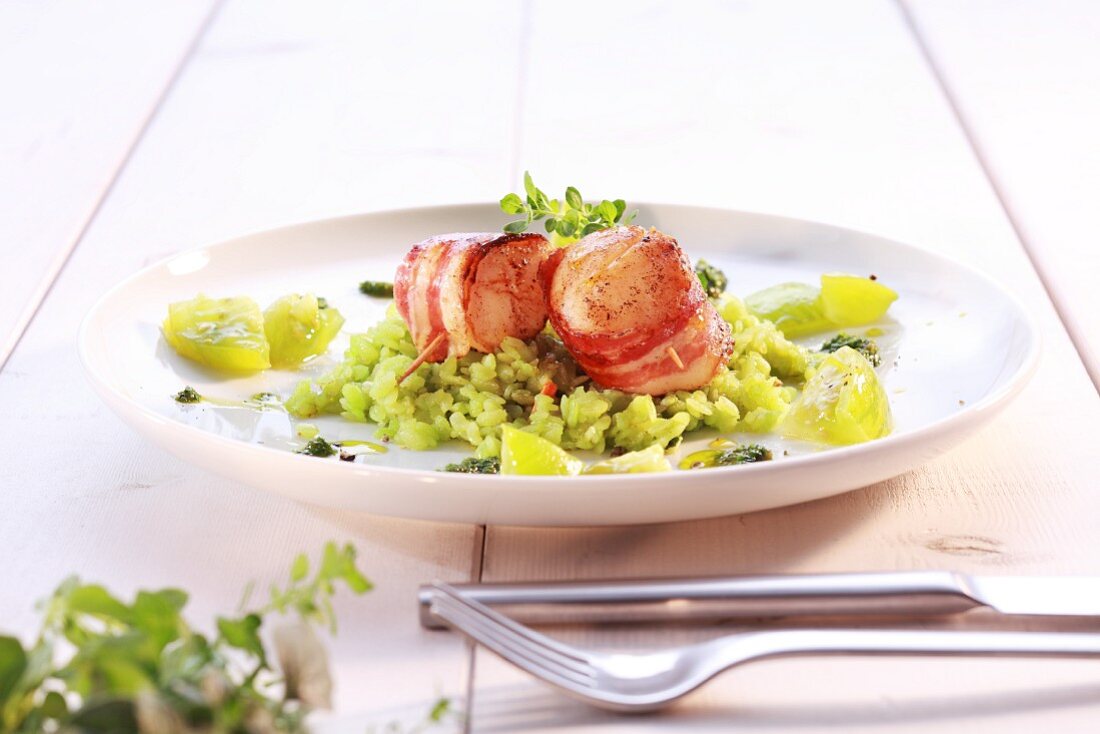 Scallops wrapped in bacon on green rice