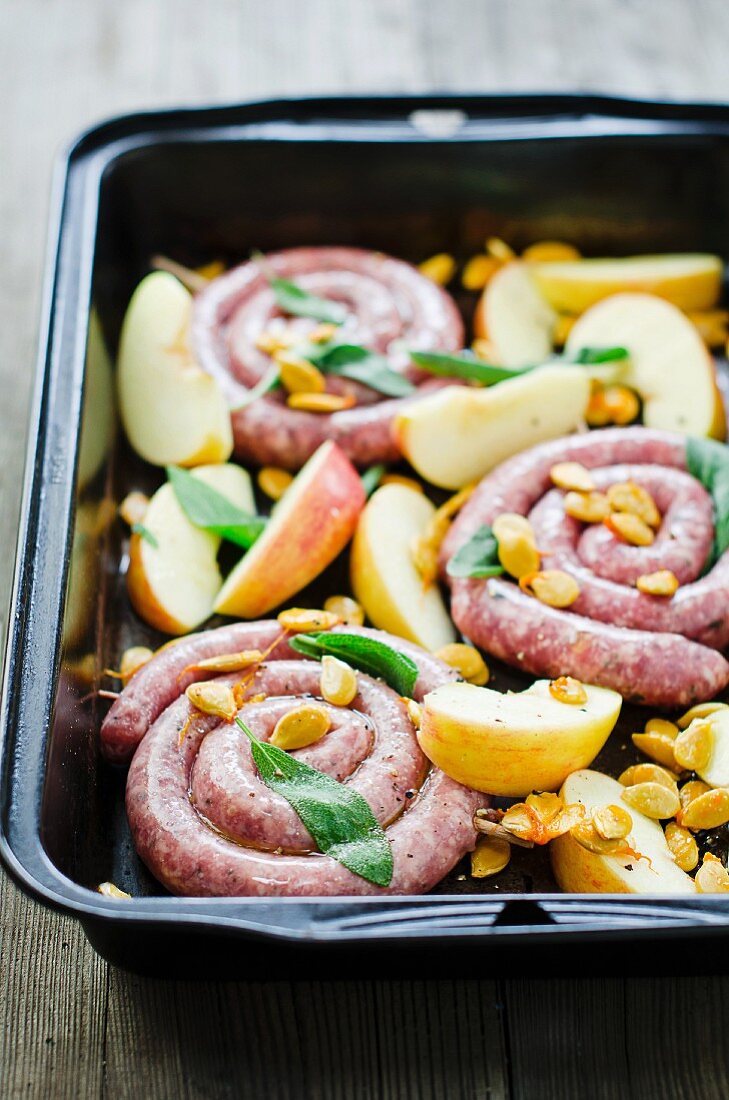 Coiled sausages with apple, sage and pumpkin seeds in a roasting tin