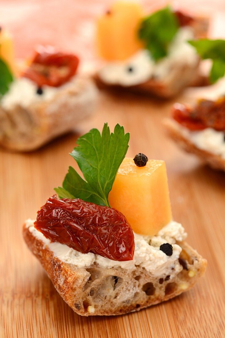 Baguette topped with cheese, pepper, melon and dried tomatoes