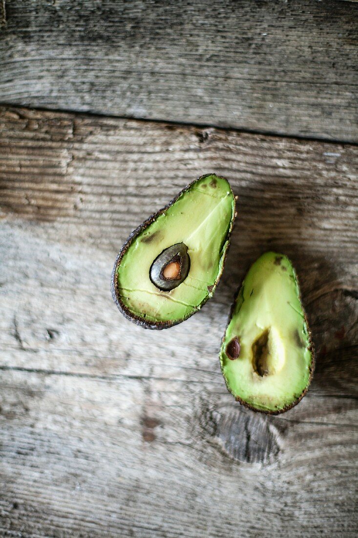 A halved avocado on a wooden surface