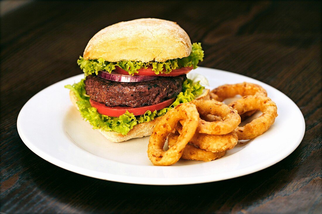 A beefburger with fried onion rings