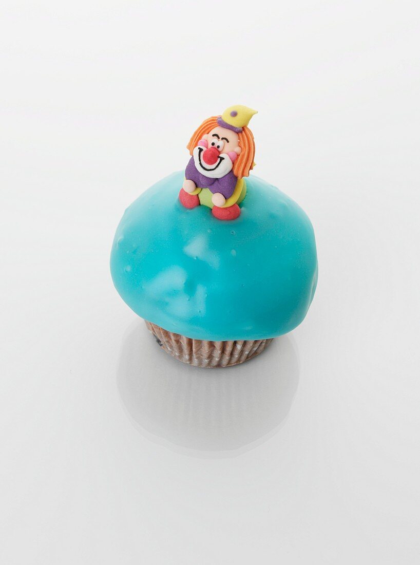 A turquoise cupcake decorated with a clown
