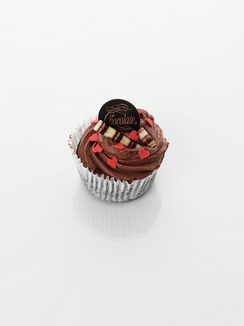 A cupcake decorated with chocolate cream and hearts