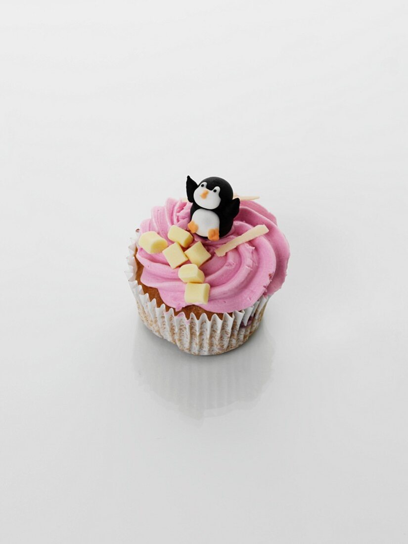 A cupcake decorated with strawberry cream and penguin