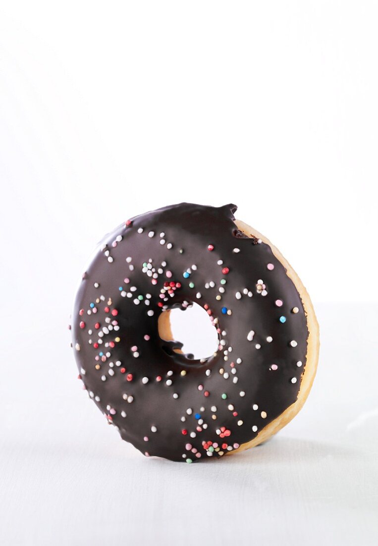 A doughnut with chocolate glaze and colourful sugar sprinkles