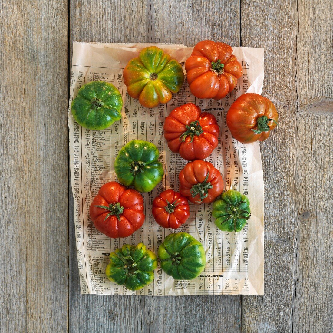 Red and green beefsteak tomatoes on a piece of newspaper