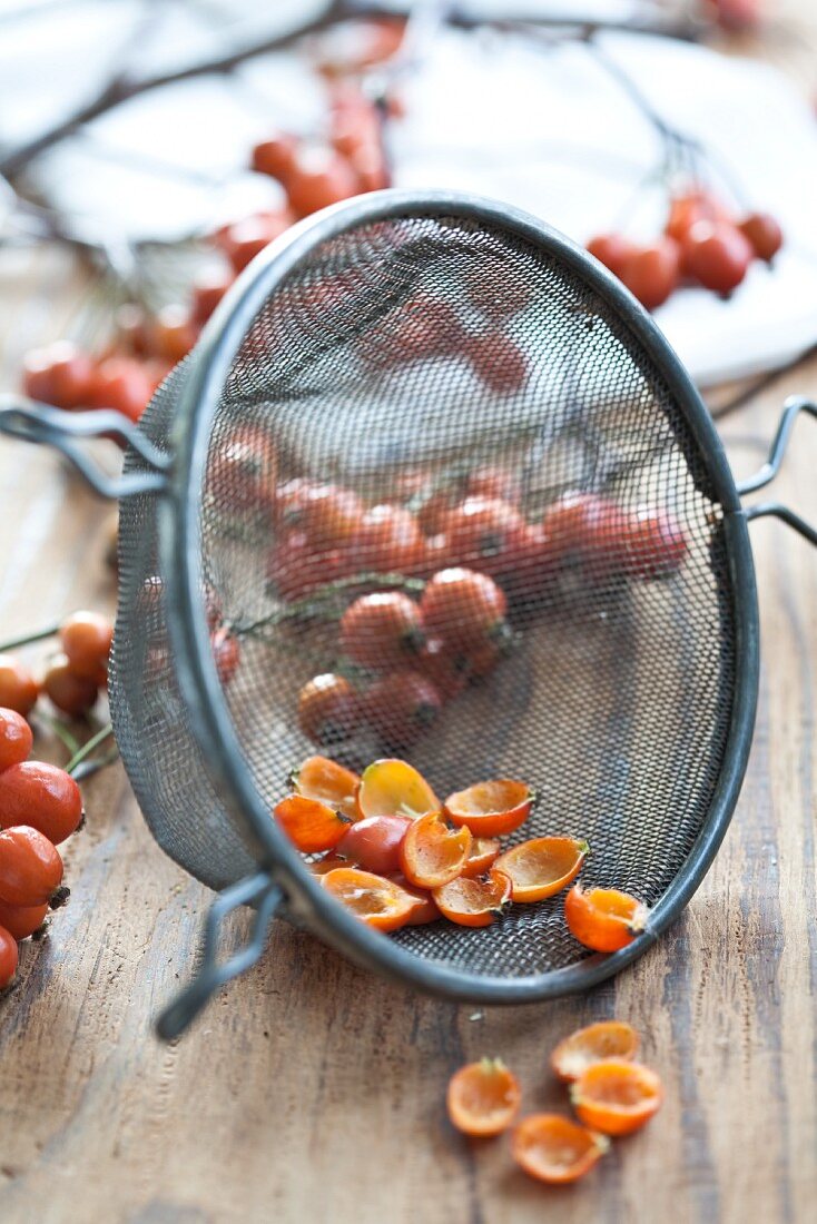 Hawthorn berries, cut in half, with seeds in a sieve