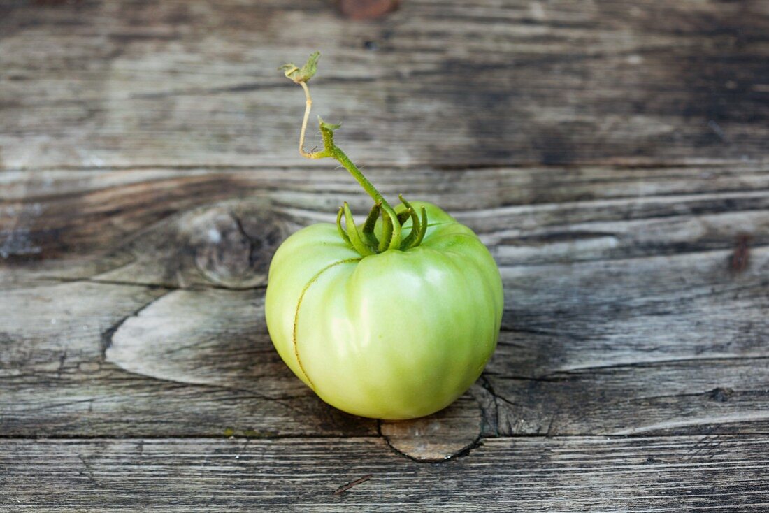 A green tomato on a wooden surface