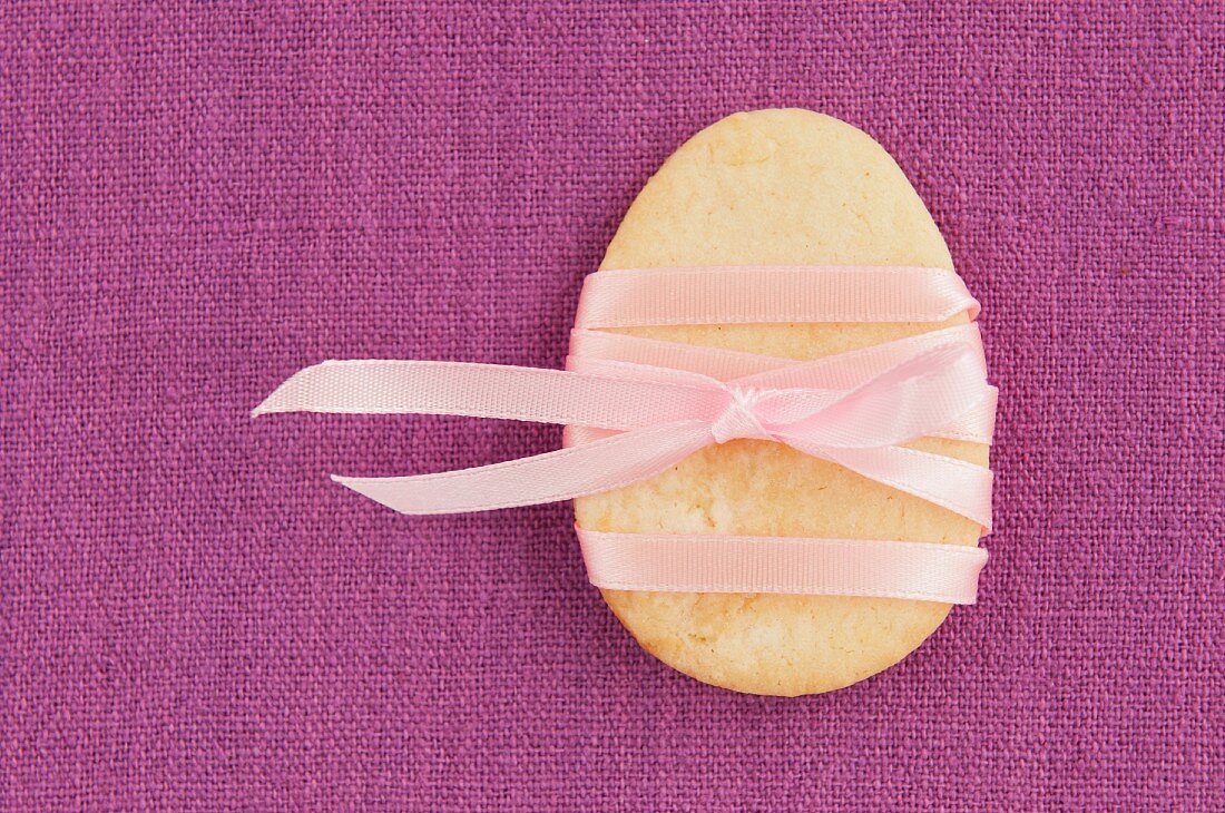 An Easter egg biscuit with a pink ribbon