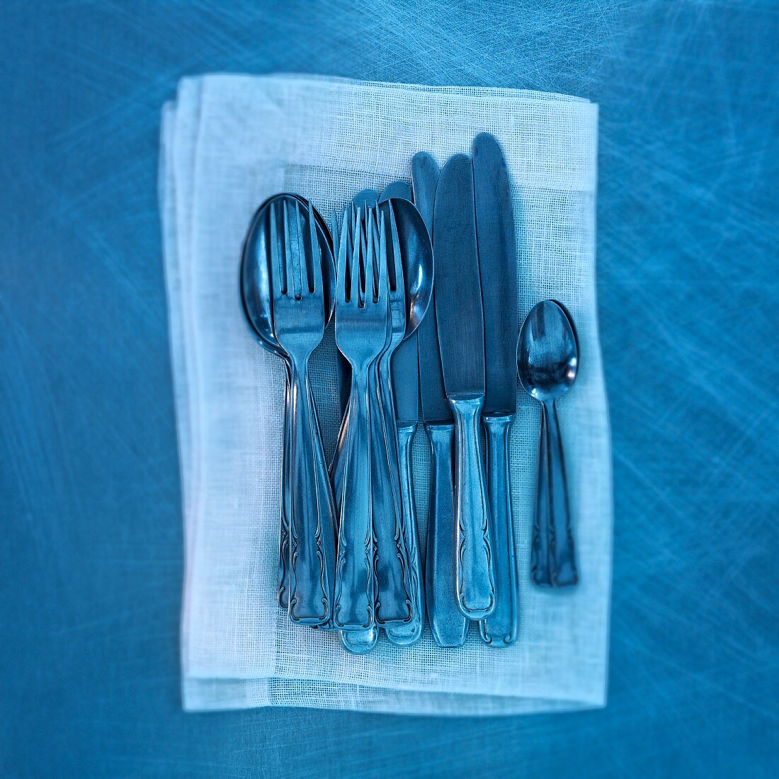 Old cutlery on a linen napkin in blue