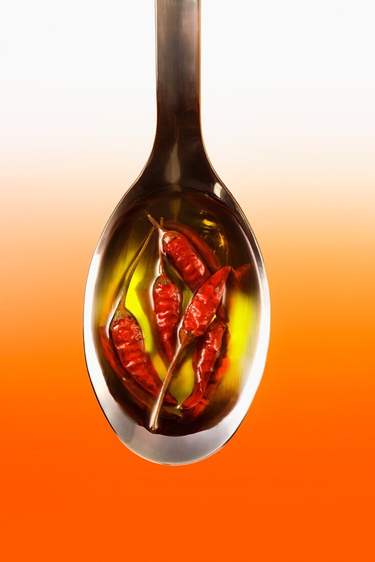 Dried chilli peppers in olive oil on a spoon
