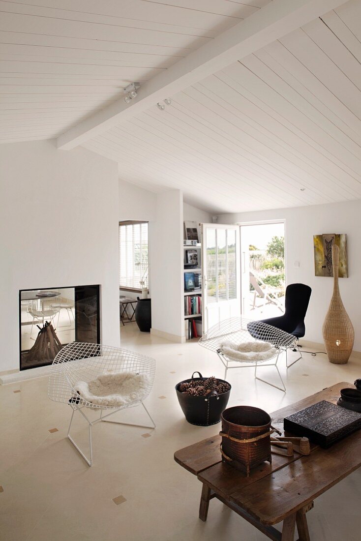 Chairs from the 50s and rustic coffee table in a simple living room with white wood ceiling