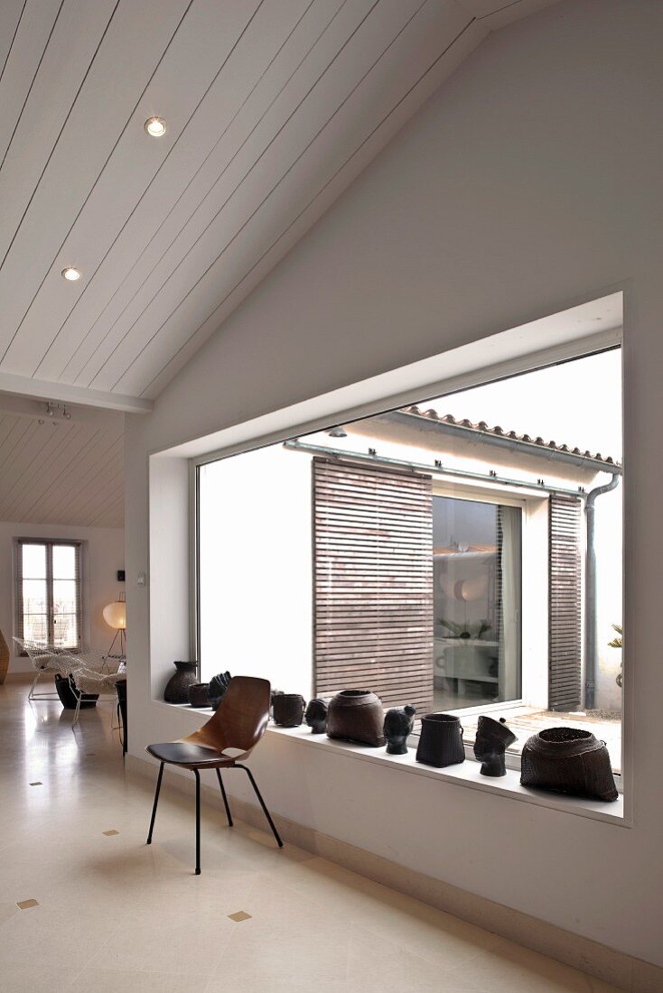 Wooden chair in front of a window with metal art objects on the window ledge and a view of a courtyard