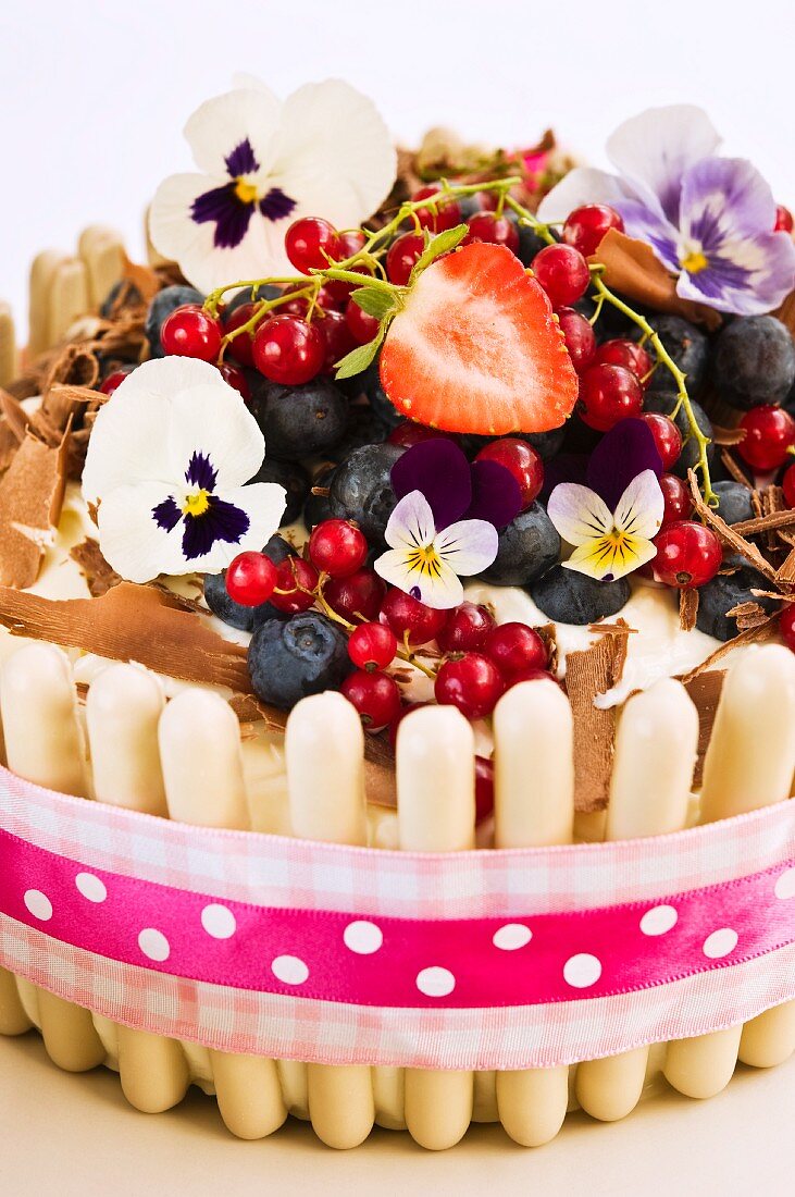 A white chocolate cake with fresh berries and pansies