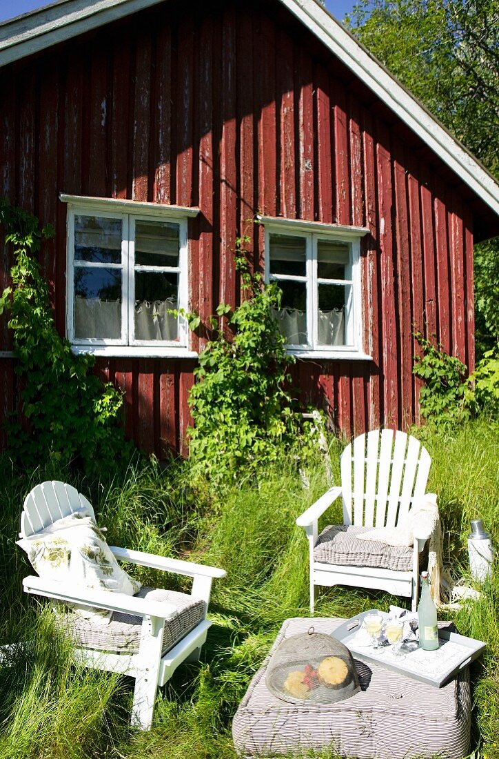 Idyllischer Sitzplatz im hohen Gras vor skandinavischem Häuschen, läd zur Zweisamkeit ein