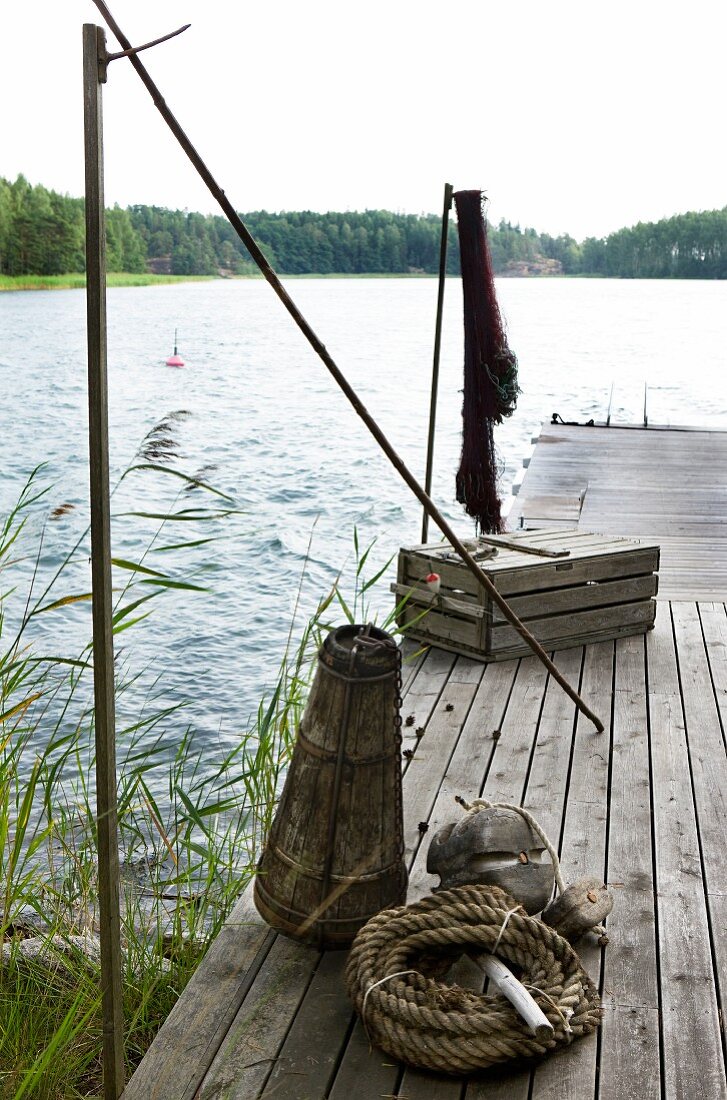 Fishing utensils on old wooden jetty next to idyllic lake