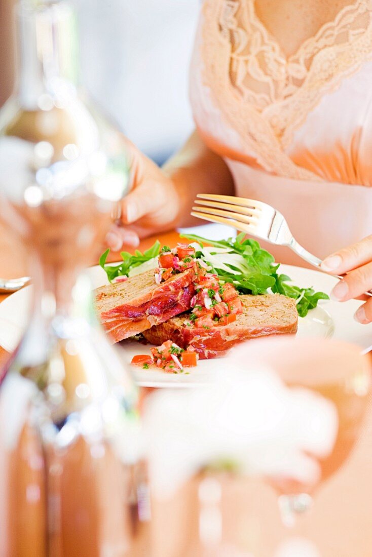 A woman eating meatloaf wrapped in bacon