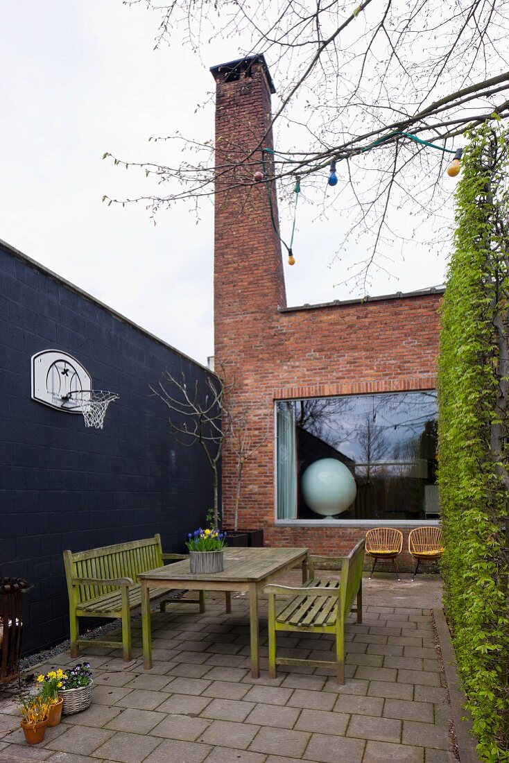 Weathered terrace furniture in courtyard of modernised house with brick facade