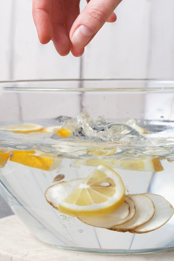 Topinamburscheiben in Zitronenwasser geben, damit sie nicht braun werden