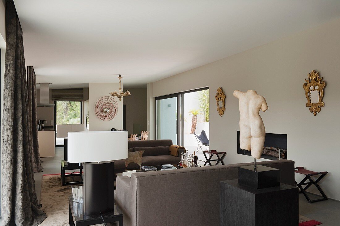 Torso on plinth in front of lounge area with sofa set in classic, modern interior