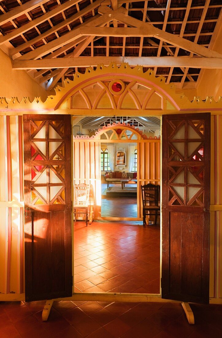 View through open doors in carved, wooden partition in traditional house