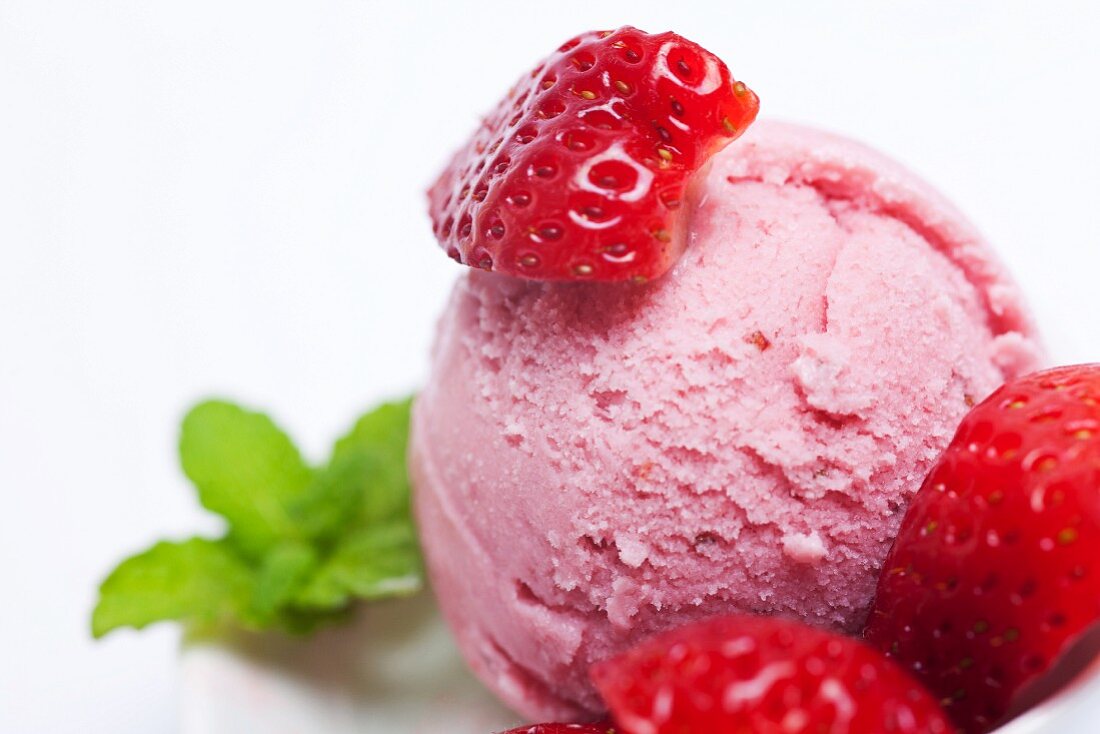 A scoop of fresh strawberry ice cream with fresh strawberries