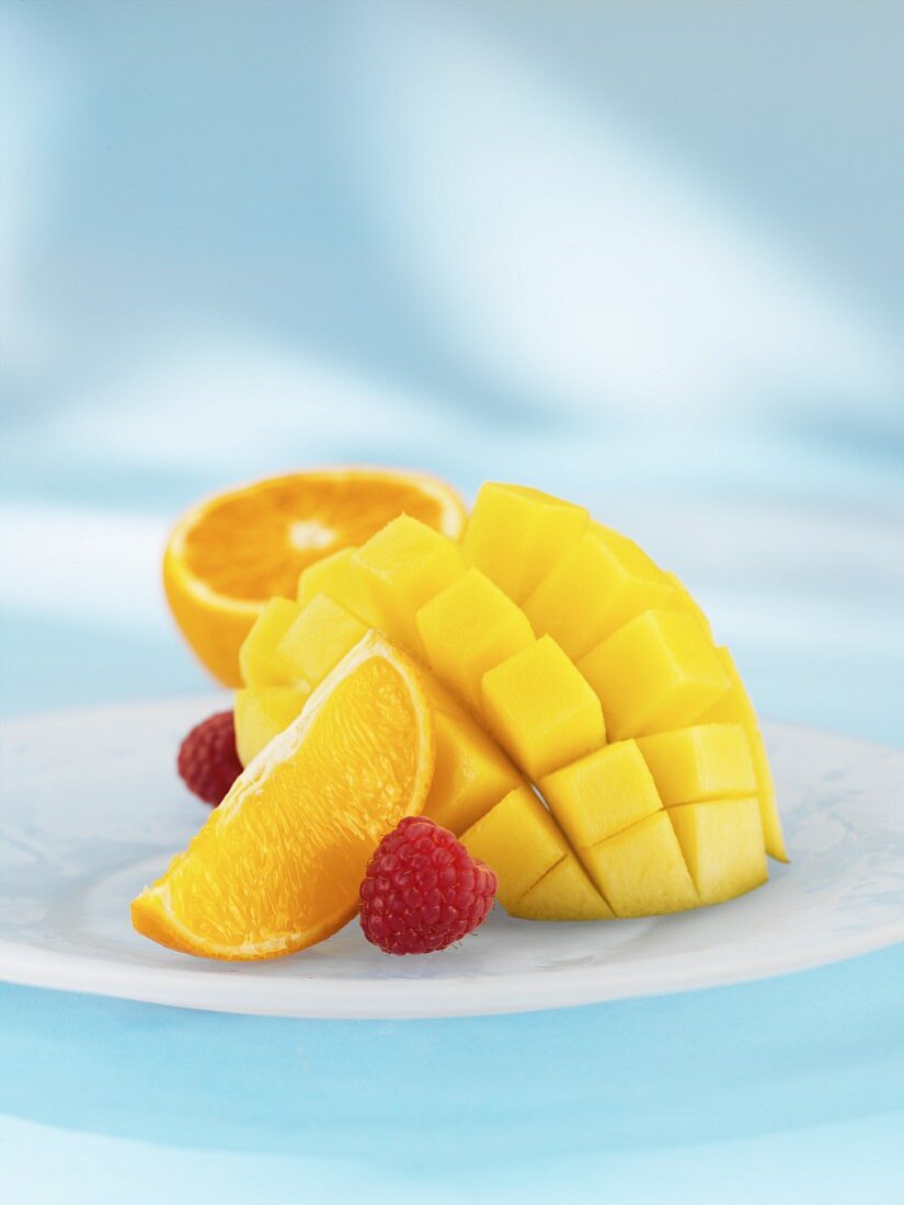 In Würfel geschnittene Mango mit Orange und Himbeeren