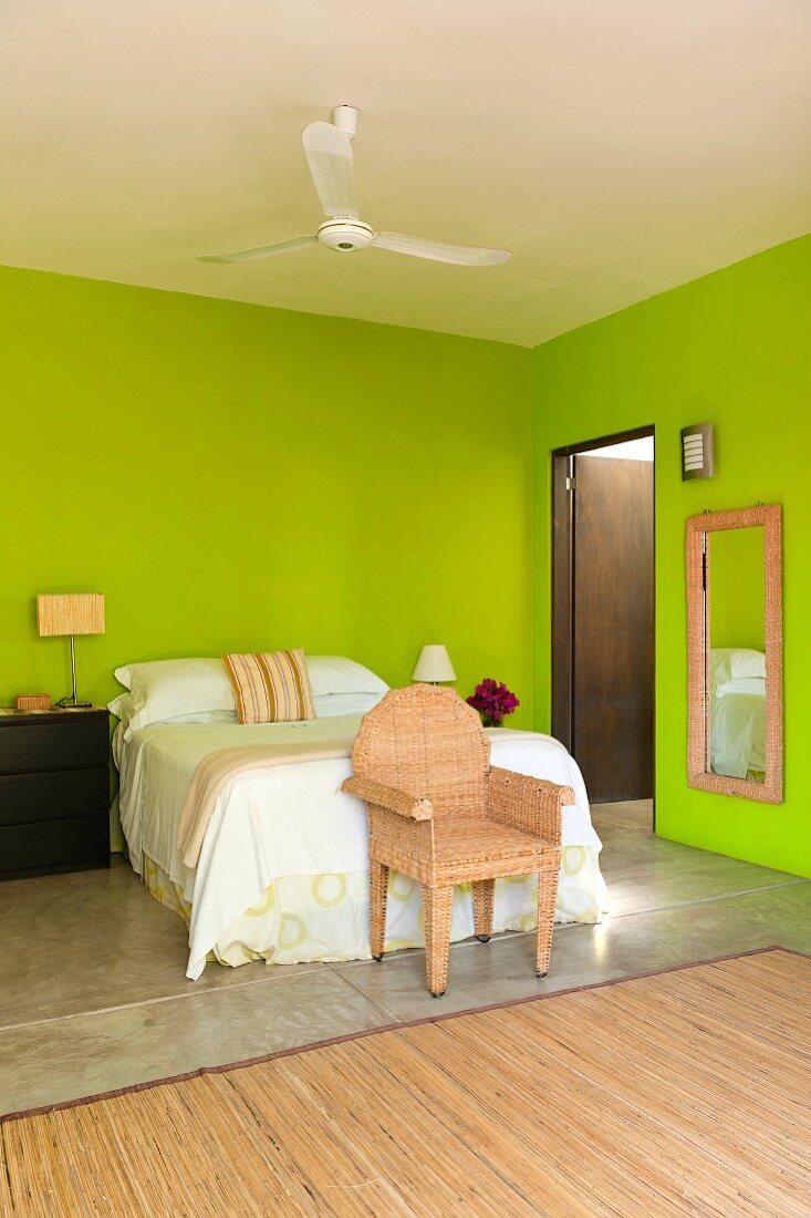 Doppelbett und Korbsessel im Schlafzimmer mit grünen Wänden
