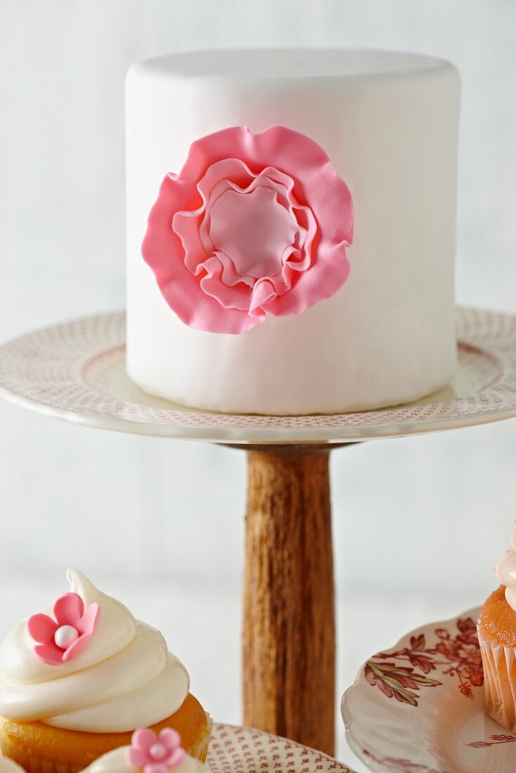 Fondant-Torte mit rosa Zuckerblüte auf Tortenständer