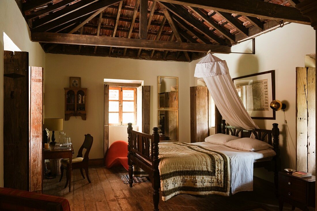 Double bed in traditional bed room of Indian residential house with exposed, wooden roof structure