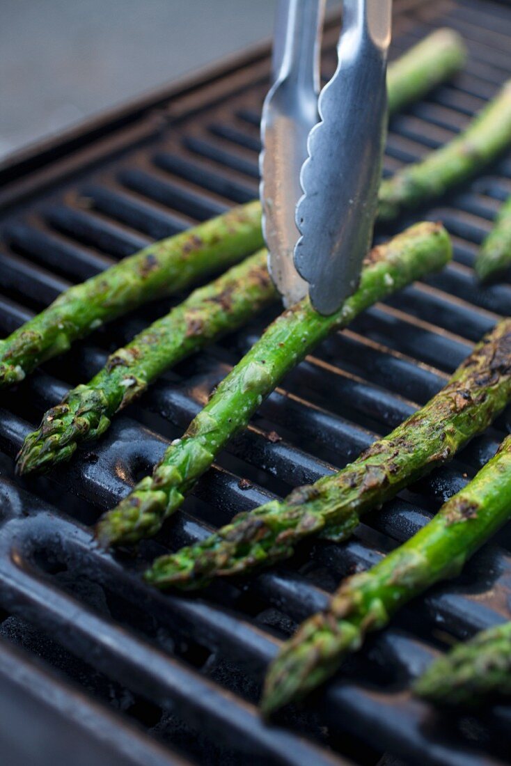 Tongs Turning Asparagus Spears on the Grill
