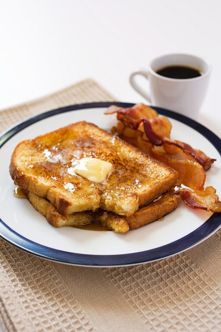 Two Slices of French Toast with Butter and Maple Syrup; Two Pieces of Bacon and a Cup of Coffee