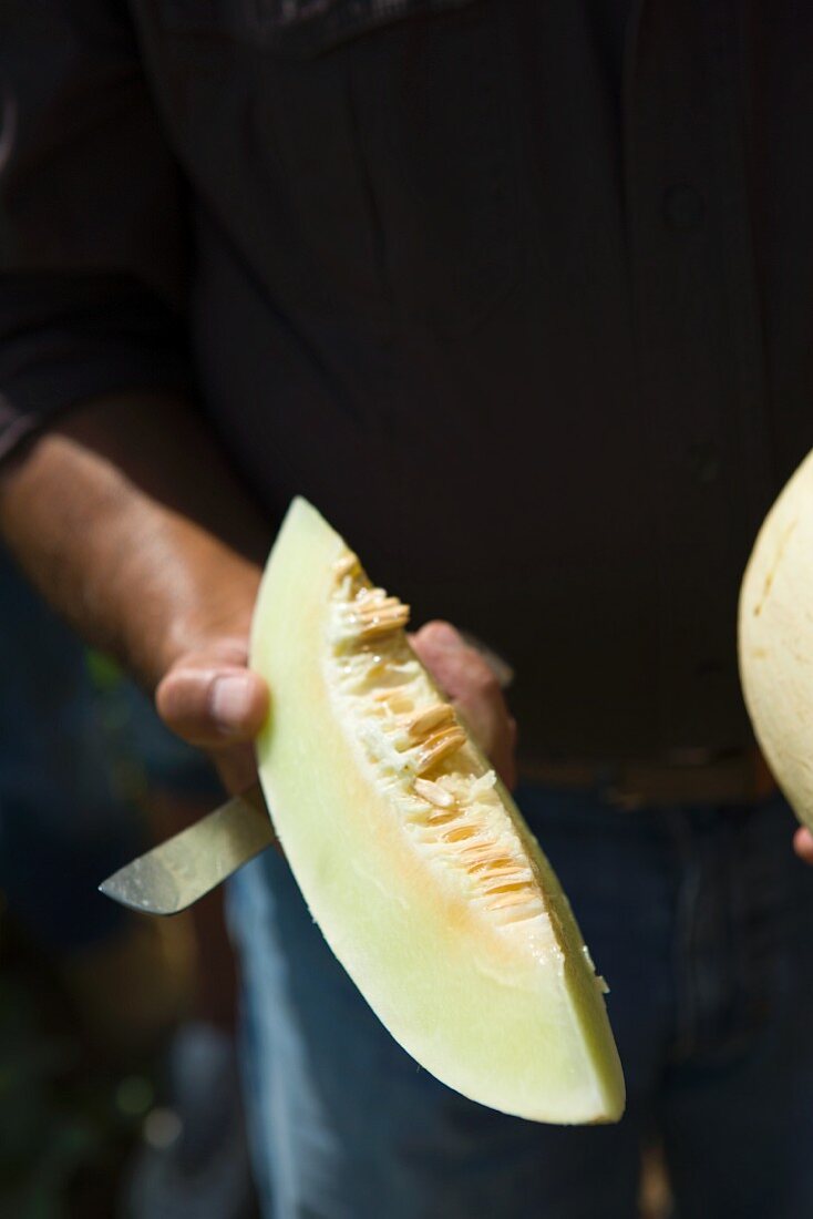 A man holding a melon wedge