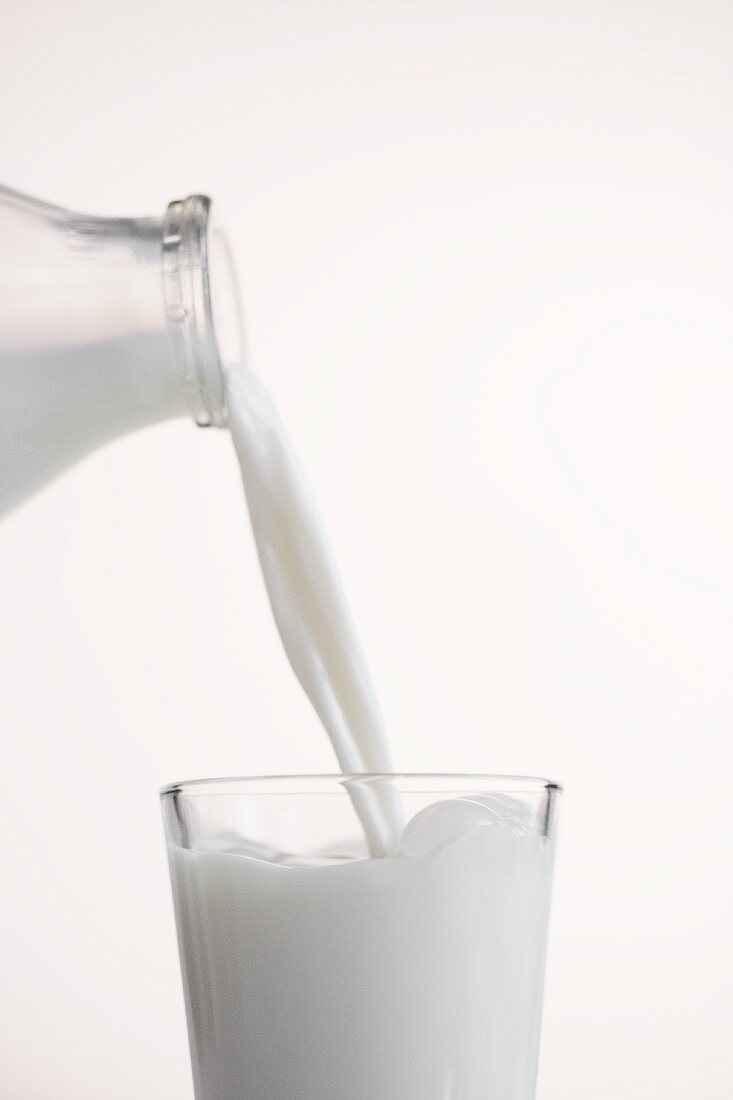 Milch aus Flasche in ein Glas gießen