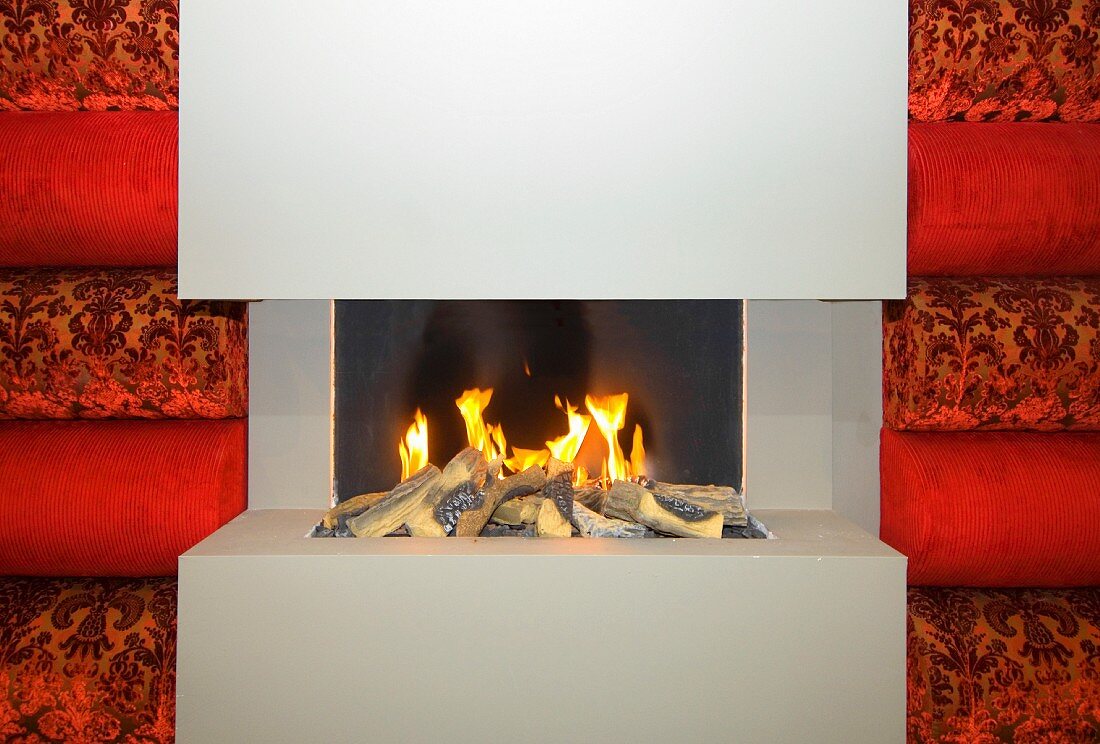 Minimalist gas fireplace in gray between red, velvet covered upholstered panels