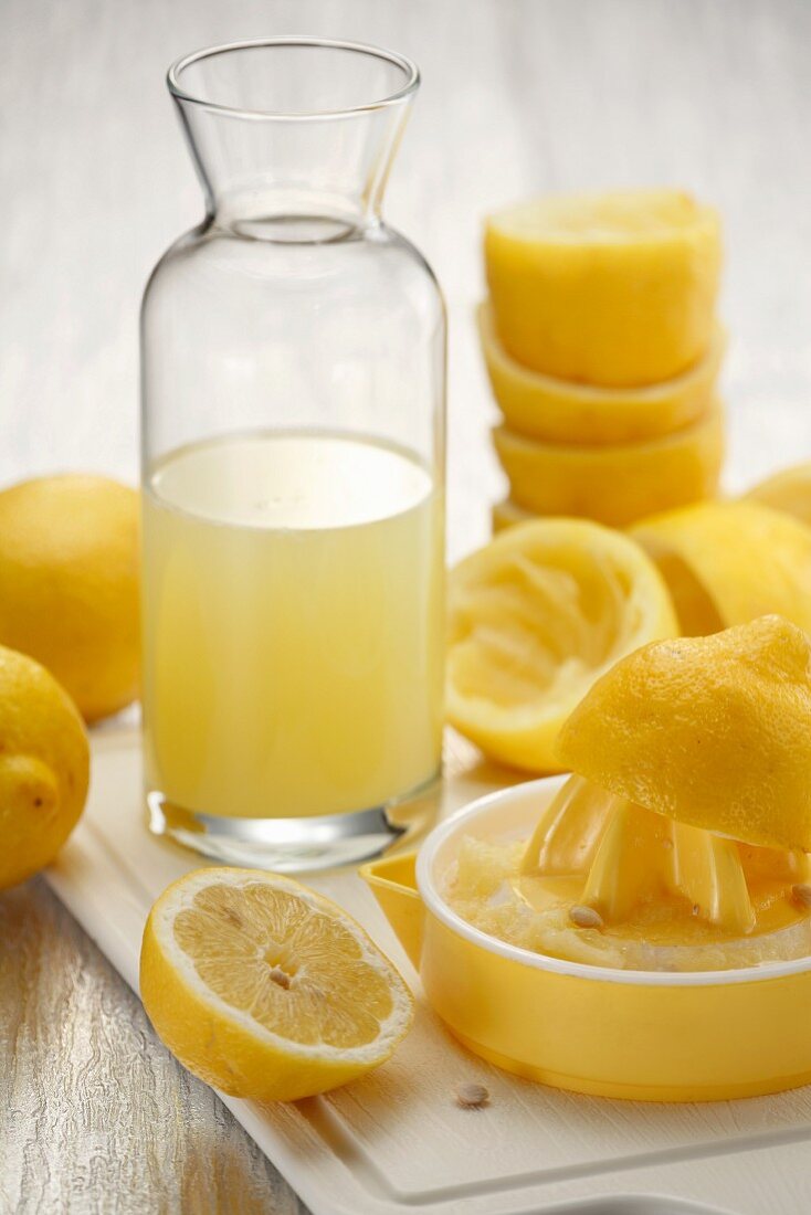 An arrangement of lemon juice, a lemon press and juiced lemons