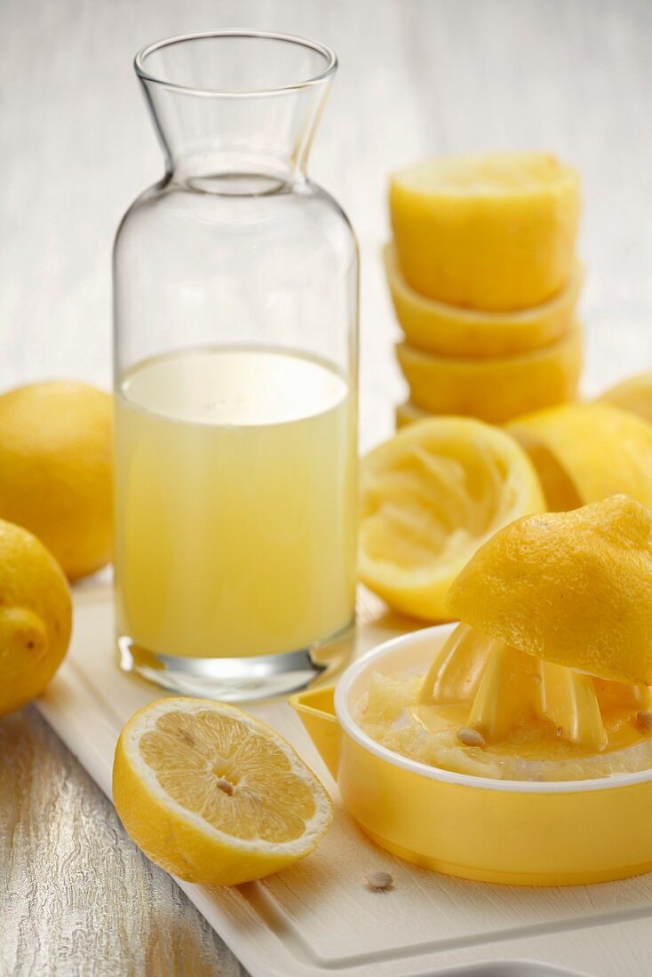 Stillleben mit Zitronensaft, Zitruspresse & ausgepressten Zitronen