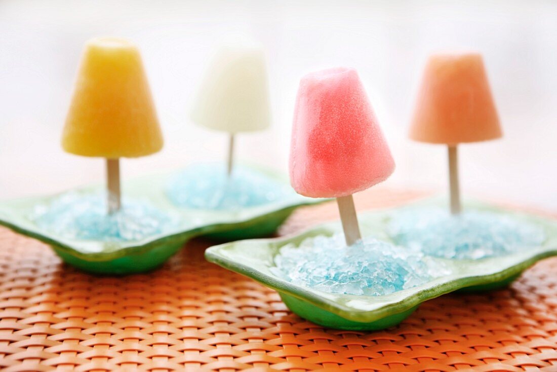 Vier Fruchteis-Popsicles in hellblauem Eis