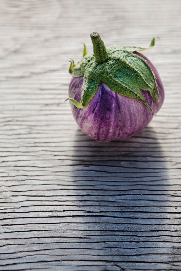 A Single Rosa Bianca Eggplant on an Aged Wooden Surface