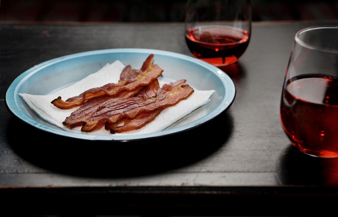 Strips of Bacon on a Plate with Glasses of Blush Wine