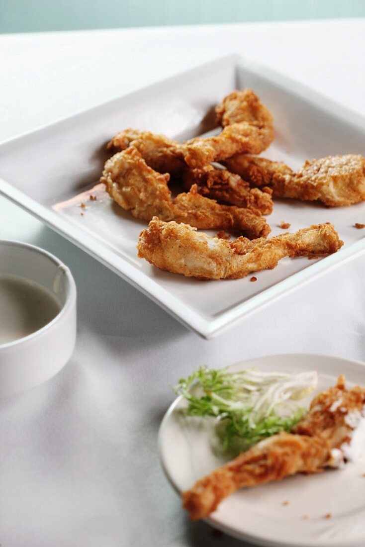 Breaded and Fried Frog Legs on a White Plate