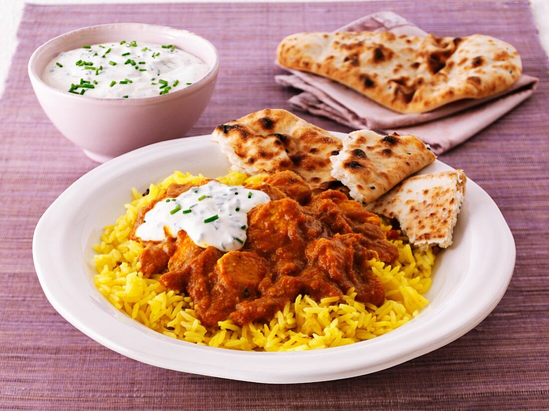 Chicken curry with rice, unleavened bread and a yoghurt dip