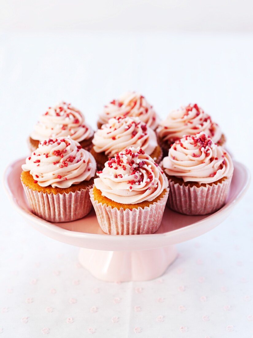 Cupcakes mit Erdbeercreme und Zuckerperlen auf Kuchenständer