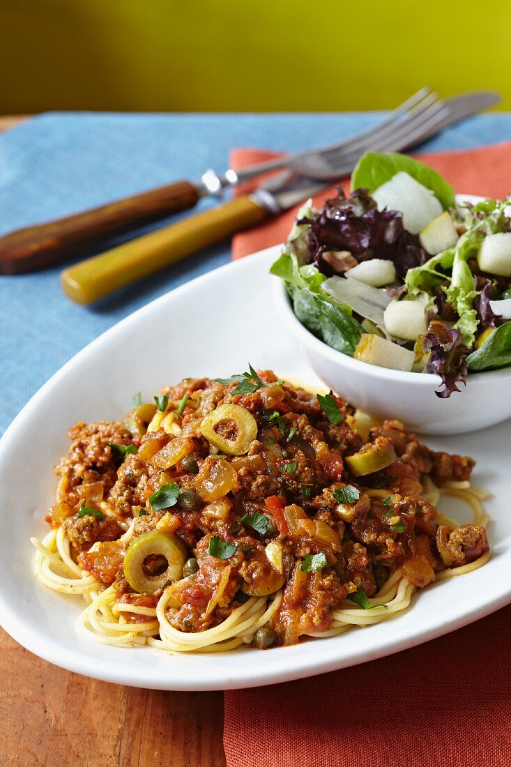 Spaghetti with mince and green olive sauce and a side salad