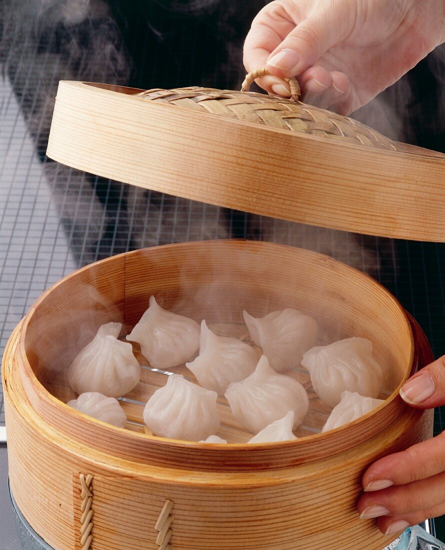 Dough parcels being steamed in a bamboo basket
