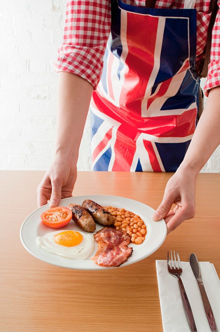 Junger Mann serviert englisches Frühstück