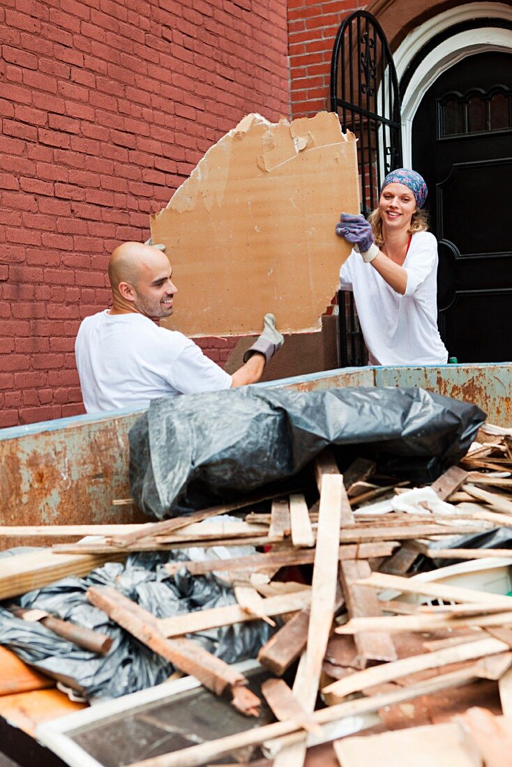 Couple filling skip with rubble