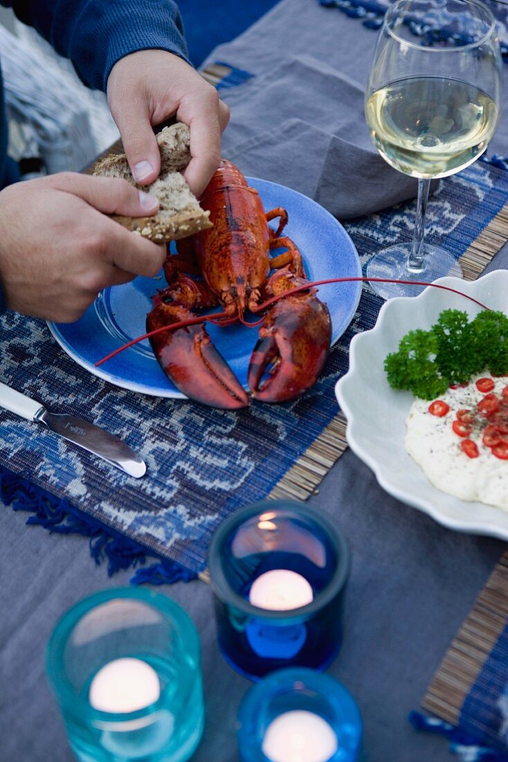 Boiled lobster with a bread roll and wine