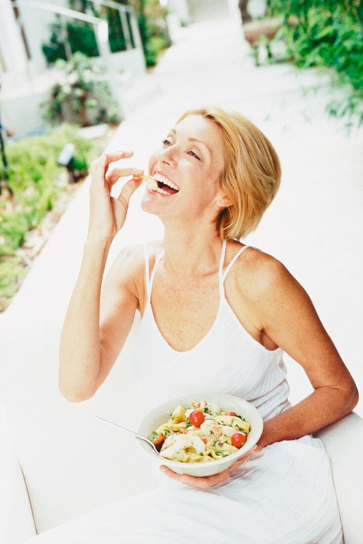 Blonde Frau isst Salat im Freien