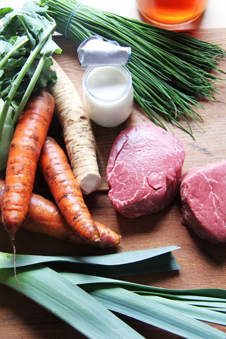 An arrangement of beef, soup vegetables, chives and a pot of cream